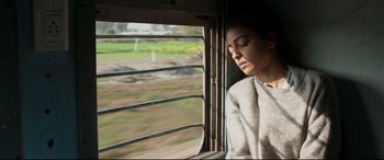 Movie still from “The Wedding Guest” (2018), directed by Michael Winterbottom – A woman sitting on a train looking out the window; Close Up shot, Low angle