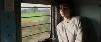 Movie still from “The Wedding Guest” (2018), directed by Michael Winterbottom – A person looking out of a train window; Medium shot, Low angle