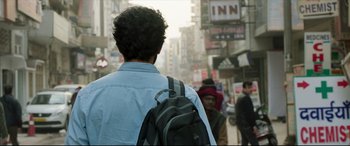 Movie still from “The Wedding Guest” (2018), directed by Michael Winterbottom – A man walking down a street with a backpack; Close Up shot, Low angle