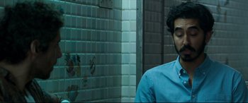 Movie still from “The Wedding Guest” (2018), directed by Michael Winterbottom – A man standing in front of a tiled wall; Close Up shot, Over the shoulder angle