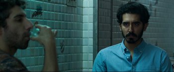 Movie still from “The Wedding Guest” (2018), directed by Michael Winterbottom – A man in a blue shirt is in a bathroom; Close Up shot, Over the shoulder angle