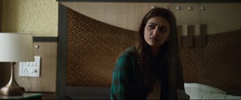 Movie still from “The Wedding Guest” (2018), directed by Michael Winterbottom – A woman in a plaid shirt is standing in front of a wall; Close Up shot, Over the shoulder angle