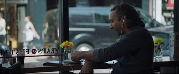 Movie still from “The Wedding Guest” (2018), directed by Michael Winterbottom – A man sitting in front of a window with a cup of coffee; Medium shot, Over the shoulder angle