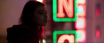 Movie still from “The Wedding Guest” (2018), directed by Michael Winterbottom – A woman standing in front of a neon sign; Close Up shot, Low angle