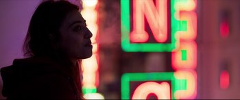 Movie still from “The Wedding Guest” (2018), directed by Michael Winterbottom – A woman standing in front of a neon sign; Close Up shot, Low angle