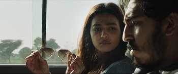 Movie still from “The Wedding Guest” (2018), directed by Michael Winterbottom – A woman holding a pair of eye glasses in front of a car window; Close Up shot, Over the shoulder angle