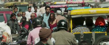 Movie still from “The Wedding Guest” (2018), directed by Michael Winterbottom – A group of people walking down a busy street; Medium shot, Low angle