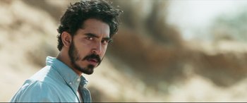 Movie still from “The Wedding Guest” (2018), directed by Michael Winterbottom – A person with a beard and mustache; Close Up shot, Over the shoulder angle