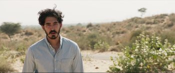 Movie still from “The Wedding Guest” (2018), directed by Michael Winterbottom – A man standing in the middle of the desert; Close Up shot, Over the shoulder angle