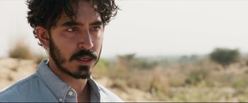 Movie still from “The Wedding Guest” (2018), directed by Michael Winterbottom – A person with a beard; Close Up shot, Over the shoulder angle