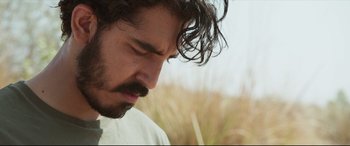 Movie still from “The Wedding Guest” (2018), directed by Michael Winterbottom – A person wearing a white shirt; Close Up shot, Low angle