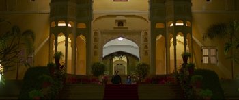 Movie still from “The Wedding Guest” (2018), directed by Michael Winterbottom – A man and a woman standing in front of an archway in a building; Extreme Wide shot, Low angle