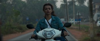 Movie still from “The Wedding Guest” (2018), directed by Michael Winterbottom – A woman riding on the back of a scooter; Medium shot, Low angle