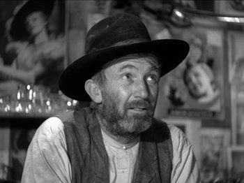 Movie still from “The Westerner” (1940), directed by William Wyler – An older man wearing a hat sitting in front of a picture; Close Up shot, Low angle