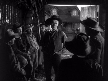 Movie still from “The Westerner” (1940), directed by William Wyler – A group of men standing next to each other in front of a building; Wide shot, Low angle