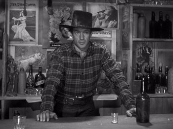 Movie still from “The Westerner” (1940), directed by William Wyler – A man standing at a bar with a hat on his head; Medium shot, Low angle