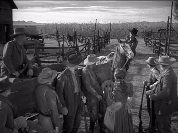 Movie still from “The Westerner” (1940), directed by William Wyler – A black and white photo of a group of men and a horse; Wide shot, High angle