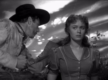 Movie still from “The Westerner” (1940), directed by William Wyler – An old black and white photo of a man and a woman; Medium shot, Low angle