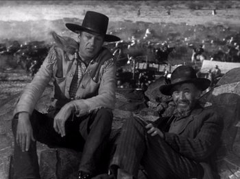 Movie still from “The Westerner” (1940), directed by William Wyler – Two men sitting next to each other on rocks; Medium shot, Low angle