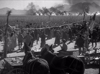 Movie still from “The Westerner” (1940), directed by William Wyler – A black and white photo of a crowd of people in a field; Extreme Wide shot, High angle