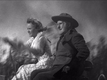 Movie still from “The Westerner” (1940), directed by William Wyler – An older man and woman sitting in a carriage; Medium shot, Low angle