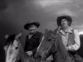 Movie still from “The Westerner” (1940), directed by William Wyler – Two men on horses in a black and white photo; Medium shot, Low angle