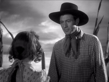 Movie still from “The Westerner” (1940), directed by William Wyler – A man and a little girl standing next to each other; Medium shot, Low angle