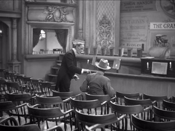 Movie still from “The Westerner” (1940), directed by William Wyler – Two men in suits and hats are sitting in a theater; Wide shot, High angle