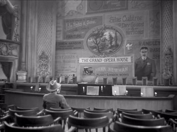 Movie still from “The Westerner” (1940), directed by William Wyler – An old photo of a man sitting in a theater; Wide shot, High angle