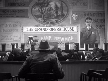 Movie still from “The Westerner” (1940), directed by William Wyler – An old photo of a man sitting in front of a bar; Wide shot, Low angle
