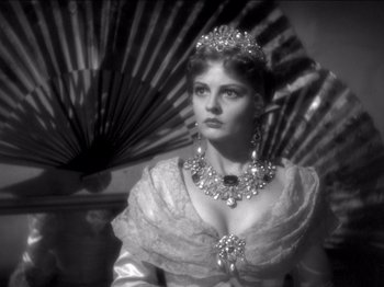 Movie still from “The Westerner” (1940), directed by William Wyler – A black and white photo of a woman wearing a tiara and holding an umbrella; Close Up shot, Over the shoulder angle