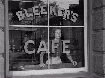 Movie still from “The Wild One” (1953), directed by Laslo Benedek – A black and white photo of a woman behind a cafe window; Medium shot, Low angle