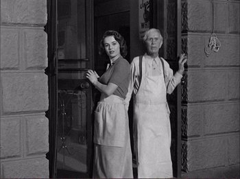 Movie still from “The Wild One” (1953), directed by Laslo Benedek – A man and a woman standing next to each other in front of a building; Medium shot, Low angle