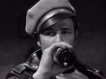 Movie still from “The Wild One” (1953), directed by Laslo Benedek – A black and white photo of a man drinking a beer; Close Up shot, Low angle