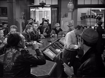 Movie still from “The Wild One” (1953), directed by Laslo Benedek – A group of people sitting at a bar; Wide shot, High angle