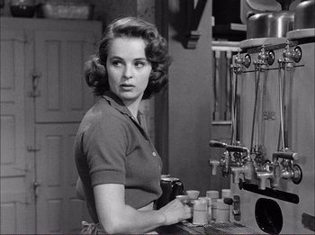 Movie still from “The Wild One” (1953), directed by Laslo Benedek – A black and white photo of a woman at a coffee machine; Medium shot, Over the shoulder angle