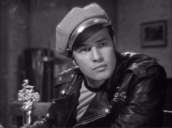 Movie still from “The Wild One” (1953), directed by Laslo Benedek – Black and white photograph of a man wearing a leather jacket and hat; Close Up shot, Low angle