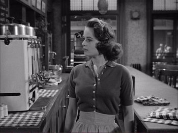 Movie still from “The Wild One” (1953), directed by Laslo Benedek – A woman standing in front of a counter in a kitchen; Medium shot, Low angle