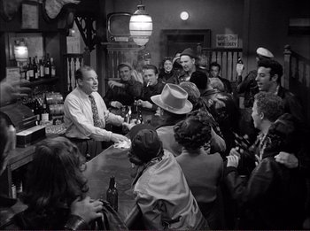 Movie still from “The Wild One” (1953), directed by Laslo Benedek – A group of people gathered around a bar; Wide shot, High angle