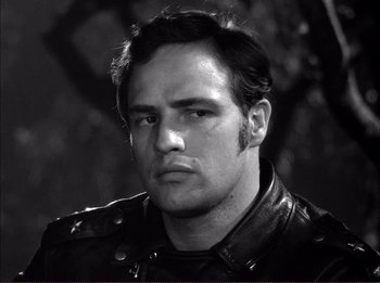 Movie still from “The Wild One” (1953), directed by Laslo Benedek – Black and white photograph of a man wearing a leather jacket; Close Up shot, Over the shoulder angle