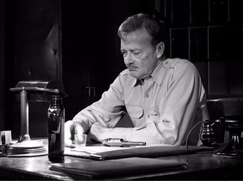 Movie still from “The Wild One” (1953), directed by Laslo Benedek – A man sitting at a table writing on a piece of paper; Medium shot, High angle