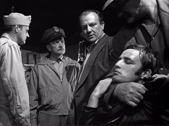 Movie still from “The Wild One” (1953), directed by Laslo Benedek – A group of men standing next to each other in a room; Medium shot, Low angle