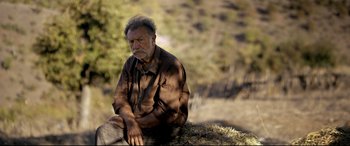 Movie still from “The Wild Pear Tree” (2018), directed by Nuri Bilge Ceylan – An old man sitting on top of a hill; Close Up shot, Low angle