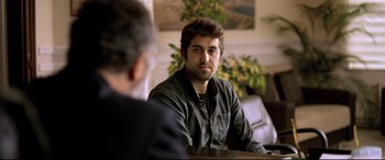 Movie still from “The Wild Pear Tree” (2018), directed by Nuri Bilge Ceylan – A man sitting in front of another man in front of a table; Medium shot, Over the shoulder angle