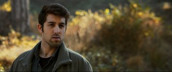 Movie still from “The Wild Pear Tree” (2018), directed by Nuri Bilge Ceylan – A person wearing a jacket near some bushes; Close Up shot, Over the shoulder angle