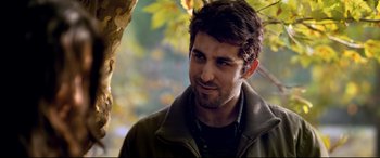 Movie still from “The Wild Pear Tree” (2018), directed by Nuri Bilge Ceylan – A person wearing a jacket near a tree; Close Up shot, Over the shoulder angle