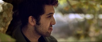 Movie still from “The Wild Pear Tree” (2018), directed by Nuri Bilge Ceylan – A man's face with trees in the background; Close Up shot, Low angle