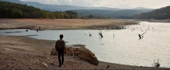 Movie still from “The Wild Pear Tree” (2018), directed by Nuri Bilge Ceylan – A man standing on the shore of a body of water; Extreme Wide shot, High angle