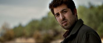 Movie still from “The Wild Pear Tree” (2018), directed by Nuri Bilge Ceylan – A person wearing a jacket with trees in the background; Close Up shot, Low angle