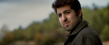Movie still from “The Wild Pear Tree” (2018), directed by Nuri Bilge Ceylan – A person wearing a jacket with trees in the background; Close Up shot, Low angle